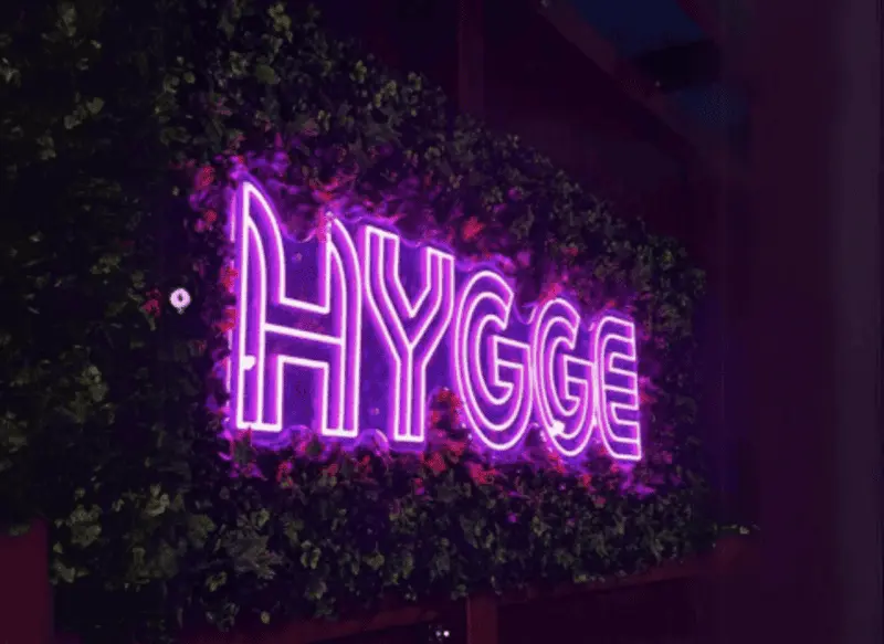 Fialový neónový nápis Hygge v zeleni — realizácia Neonworld